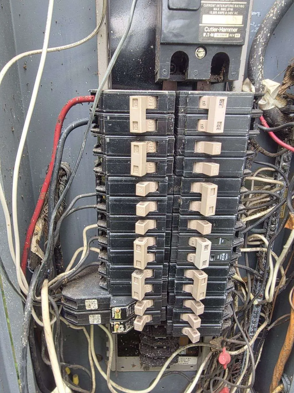 Corroded breakers and tangled wiring inside an older panel on a fire-damage call
