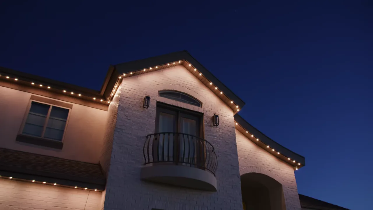 Two-story home with warm white JellyFish Lighting points along the eaves and gable above a balcony at dusk
