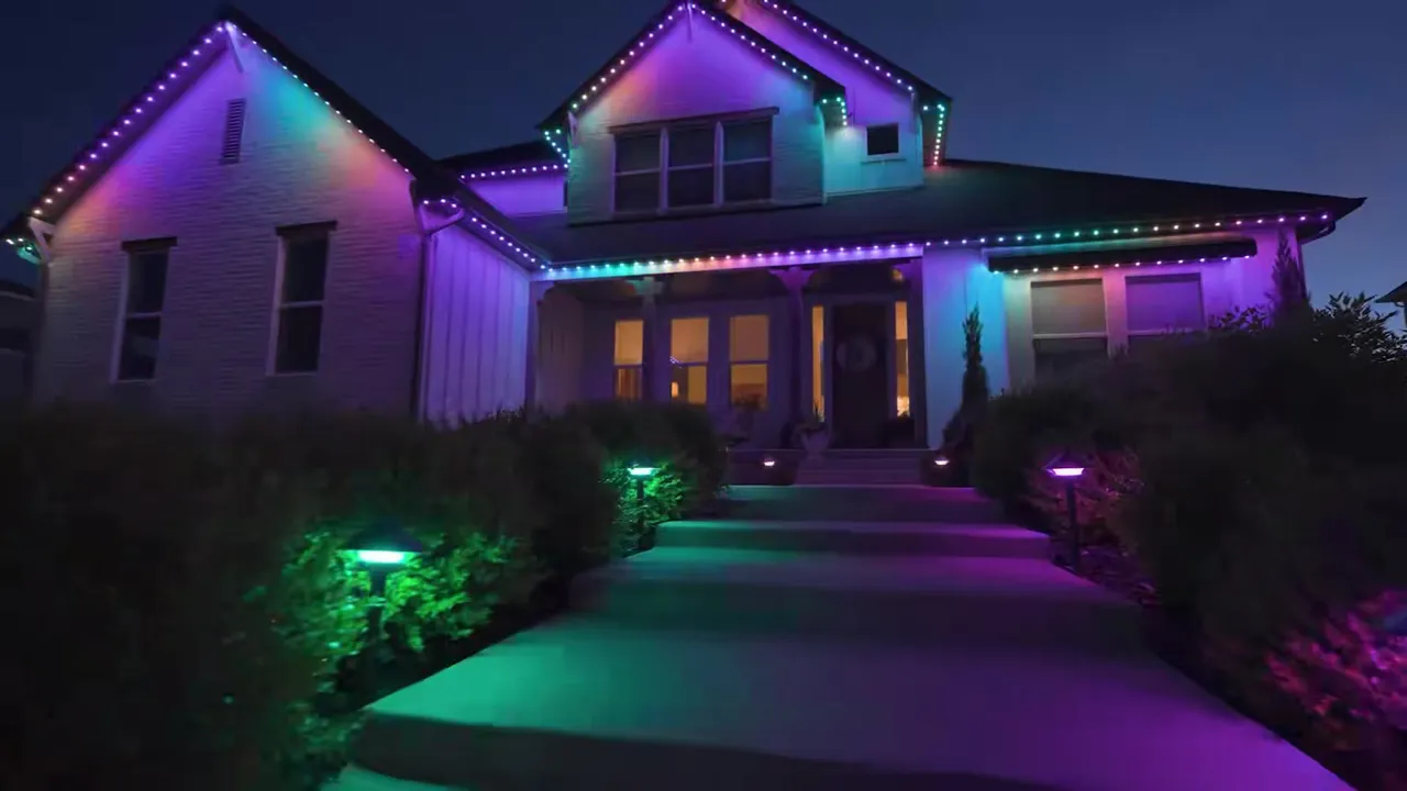 Two-story gabled home with multicolor JellyFish Lighting holiday scene along the rooflines at dusk