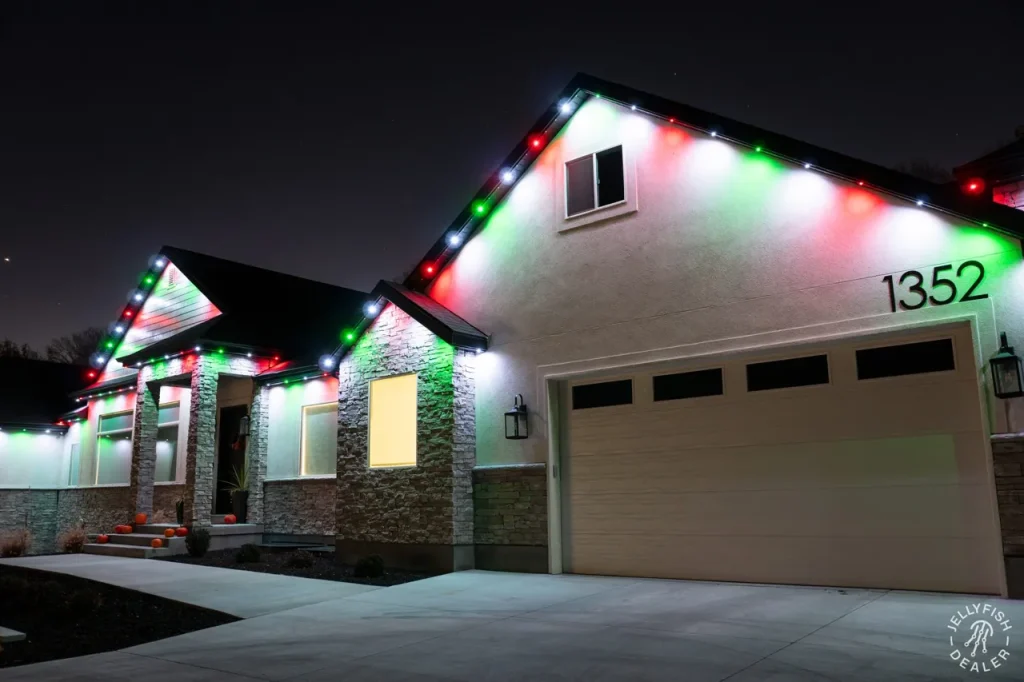 Candy-cane red and white JellyFish permanent Christmas lights over a garage peak