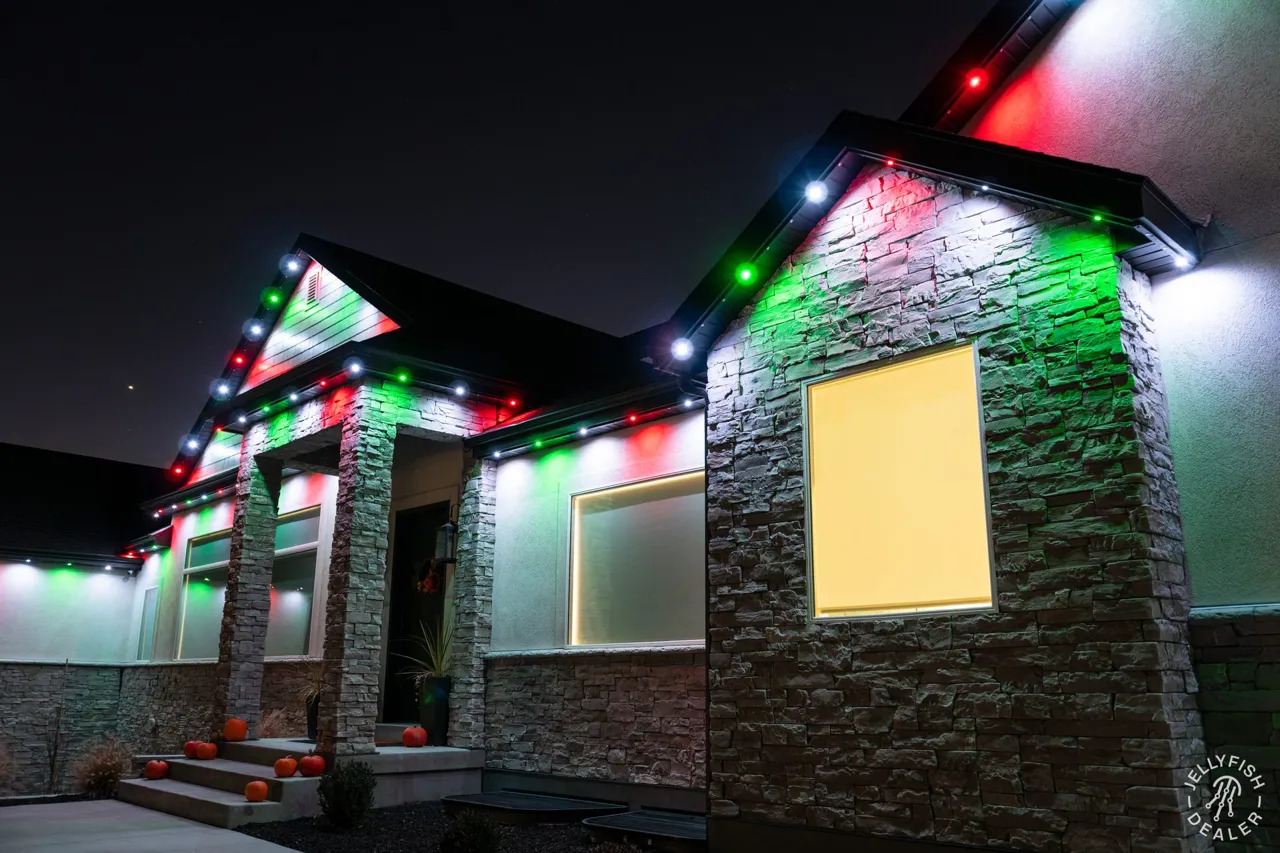Stone-front home with JellyFish permanent Christmas lights tracing each gable