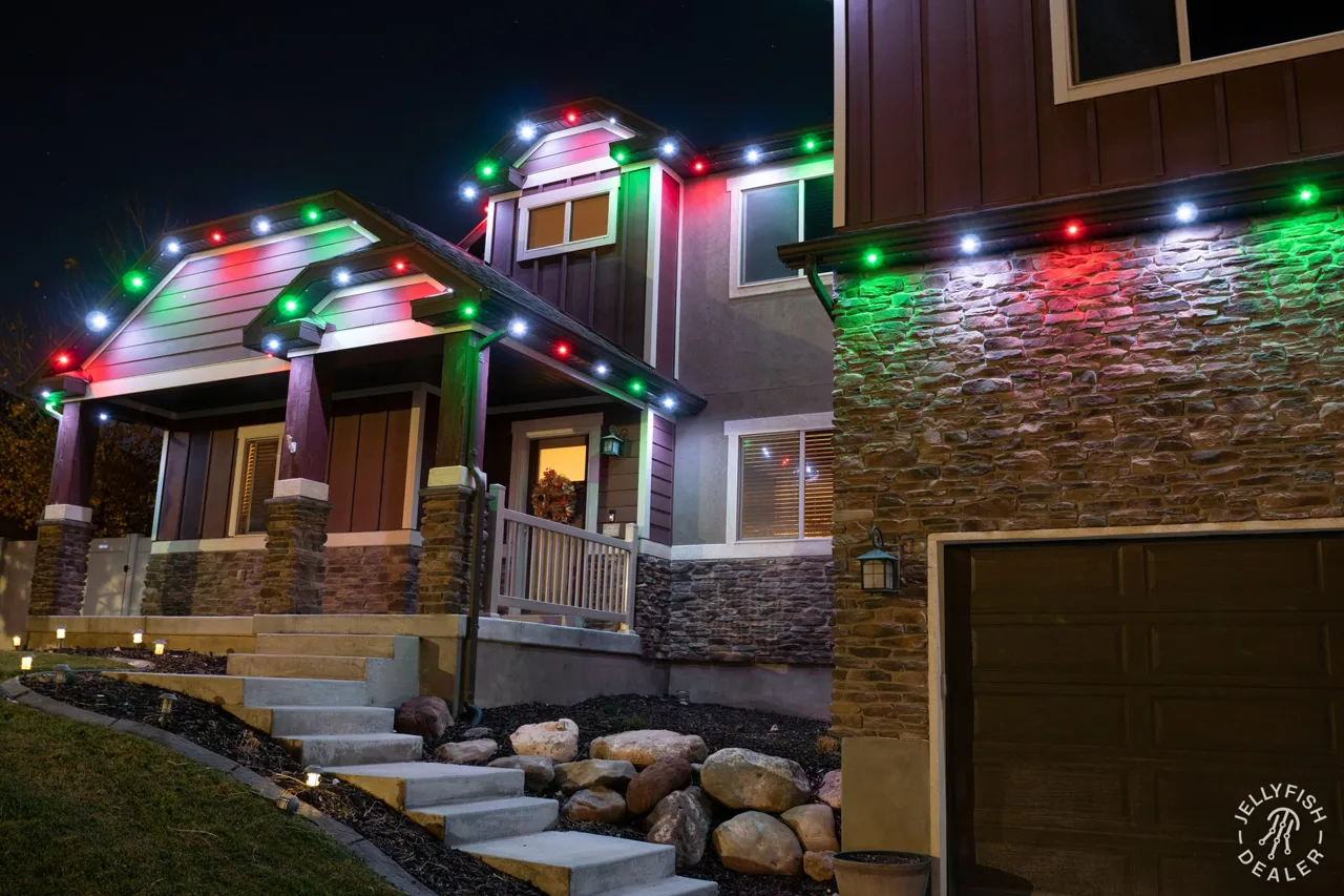 Home with a stair entry and JellyFish permanent lights in holiday colors along the roof