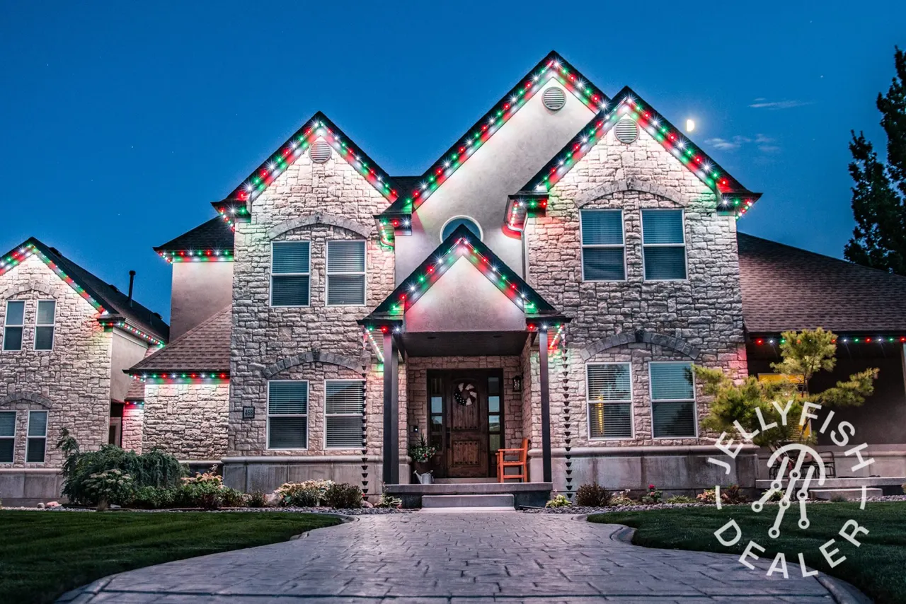 Stone estate home with classic white JellyFish permanent lights on every gable