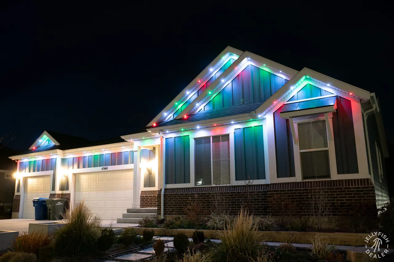 Wide two-story home with multicolor JellyFish permanent lights along the full roofline