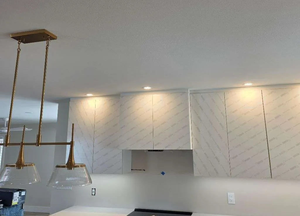 Kitchen with a brass linear pendant and recessed lights above new cabinets