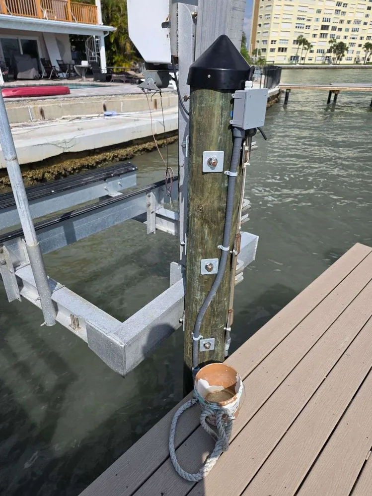 Before: weathered electrical boxes and loose wiring on a dock piling in St. Petersburg, FL