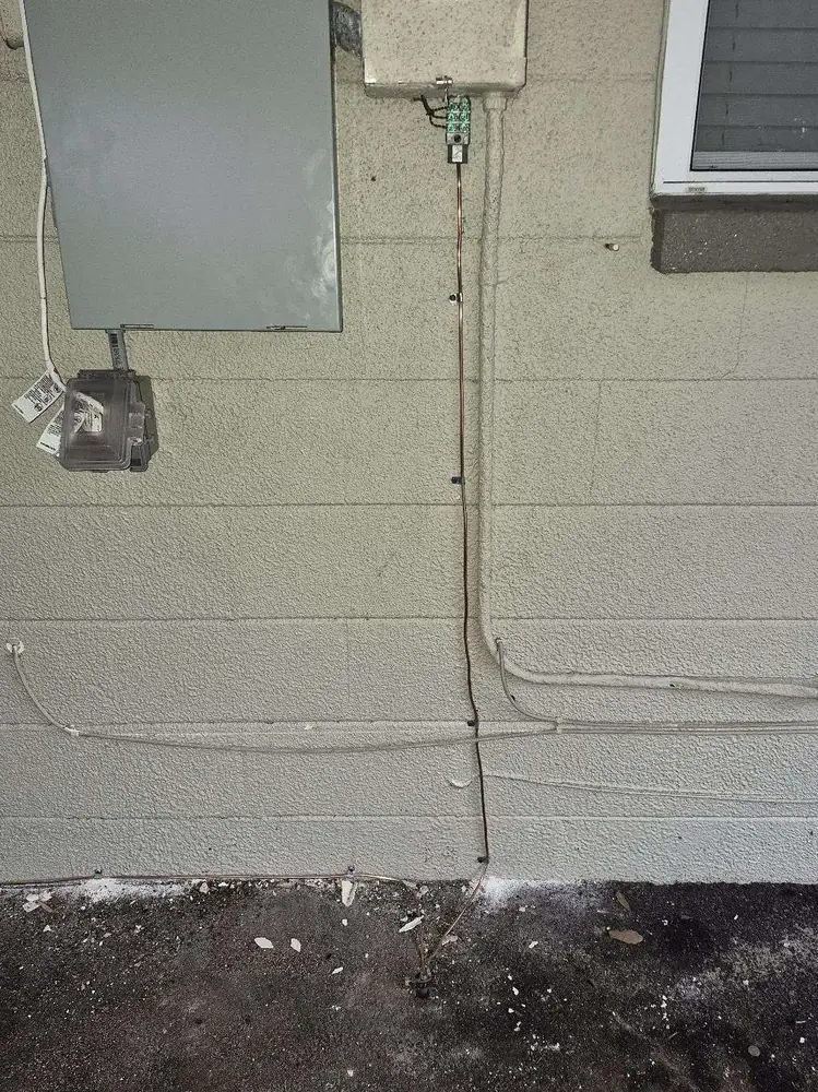 Panel replacement in St. Petersburg, FL – before old exterior equipment with loose wiring on the wall