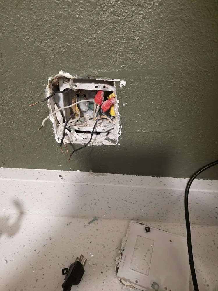 Before: damaged outlet box with exposed wiring in a Clearwater Beach hotel room