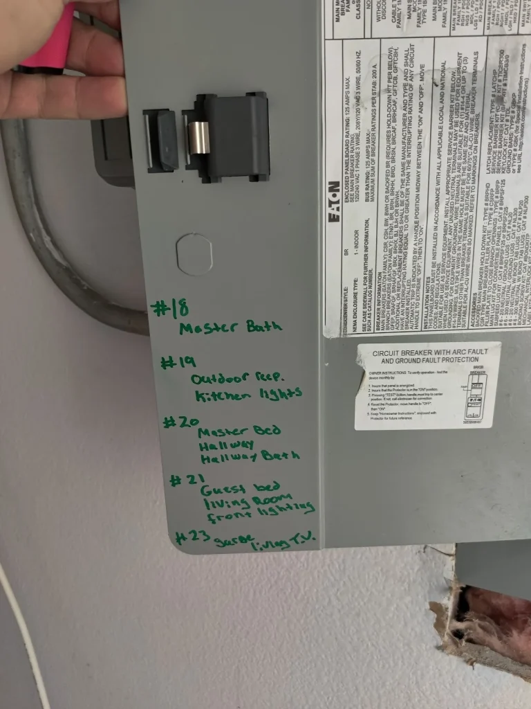 Gray breaker panel cover with a green hand-written circuit directory and an arc-fault circuit breaker label at a Pinellas County home
