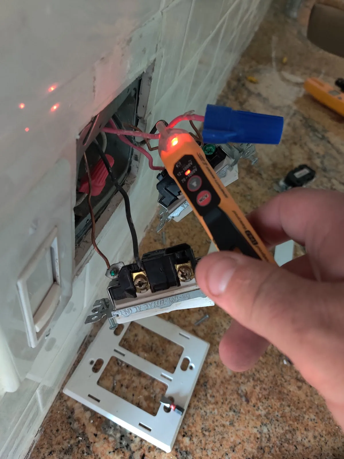 Electrical Troubleshooting in Pinellas County: Dead Outlets, Tripping Breakers and Flickering Lights Electrician testing switch-box wiring with a voltage tester during an electrical troubleshooting call in Pinellas County